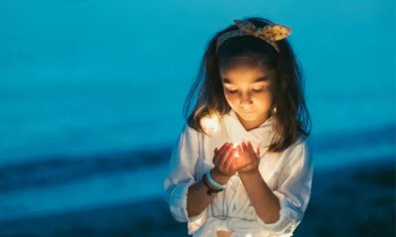 Girl holding light by the beach.