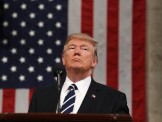Man standing before American flag, looking upward.