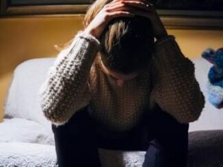 Person sitting with head in hands, distressed.