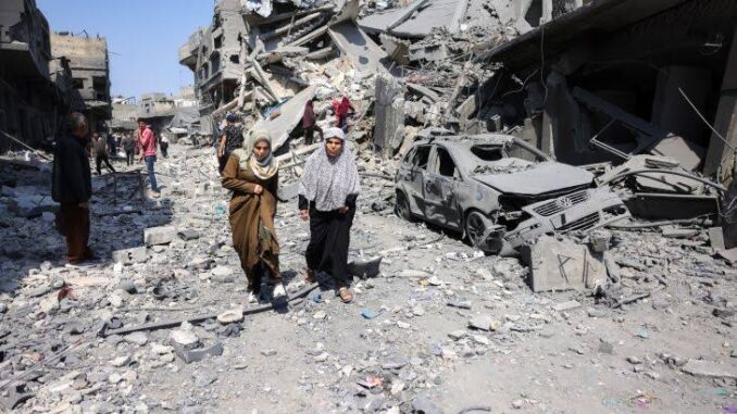 Women walking through rubble and destruction.