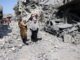 Women walking through rubble and destruction.