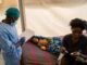 Healthcare worker attending to child and mother.