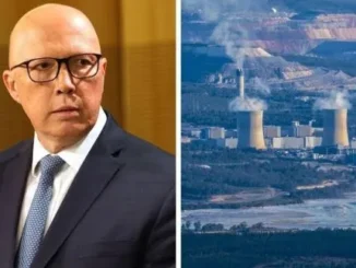 Man in suit beside industrial power plant.