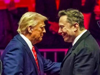 Two men smiling and clasping hands on stage