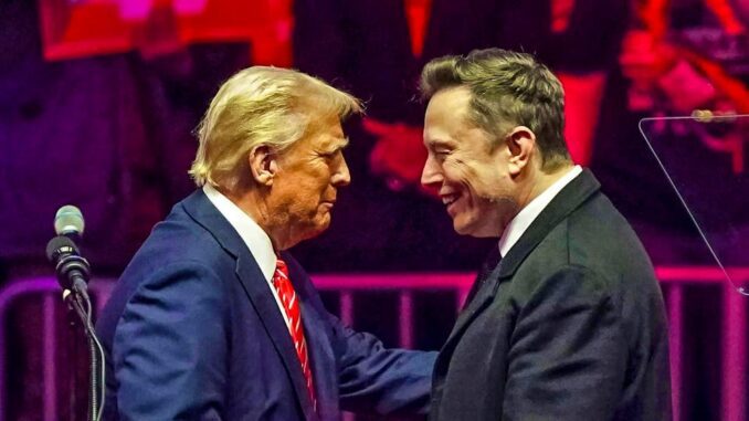 Two men smiling and clasping hands on stage