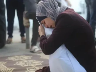 Woman sitting and holding pillow, looking emotional.