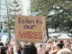 Protest crowd with "listen to our voices" sign.