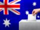 Hand voting with Australian flag background.