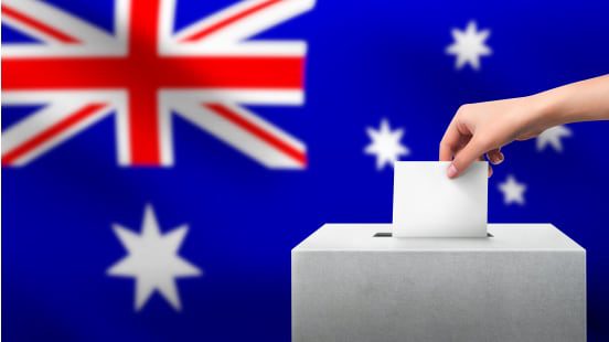 Hand voting with Australian flag background.