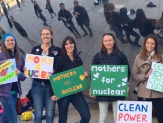 Women holding pro-nuclear energy signs outdoors.