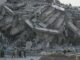 Collapsed building with rescue workers present.