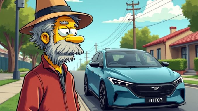An older man with a hat stands on a suburban street with a blue car behind him.