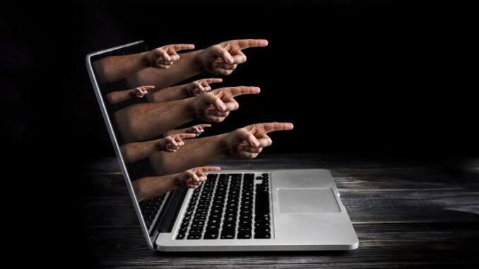 Hands emerging from laptop screen, pointing outward.