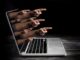 Hands emerging from laptop screen, pointing outward.