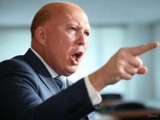 Man in suit pointing and speaking assertively.