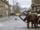 Soldiers and burning car in urban conflict.