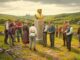 People gathered around a statue in field.