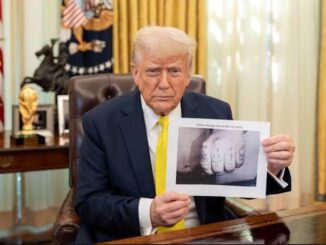 Donald Trump holding a photo of a hand with multiple fingers.