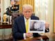 Donald Trump holding a photo of a hand with multiple fingers.