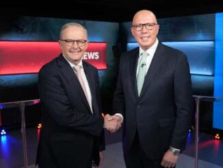 Two men in suits shaking hands in a news studio.