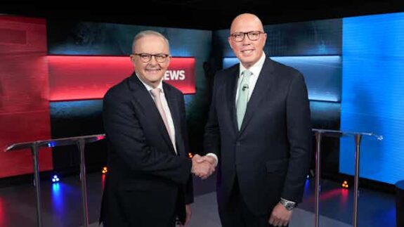 Two men in suits shaking hands in a news studio. Two men in suits shaking hands in a news studio.