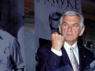 Man in suit making a rude hand gesture.