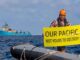 Man on a boat holding a protest sign about pacific debris.