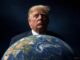 Donald Trump with a serious expression behind a globe of Earth.