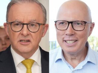 Two men wearing glasses, one in a suit and tie, the other in a casual shirt.