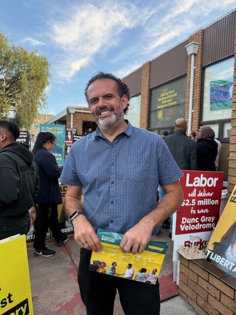 Man smiling and holding a sign supporting Labor party and 3-dollar daily wage.