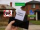 Hand holding card in front of houses.