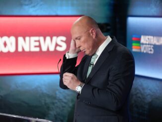 Man adjusting earpiece during news broadcast.