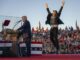 Politician speaking, person jumping enthusiastically nearby.