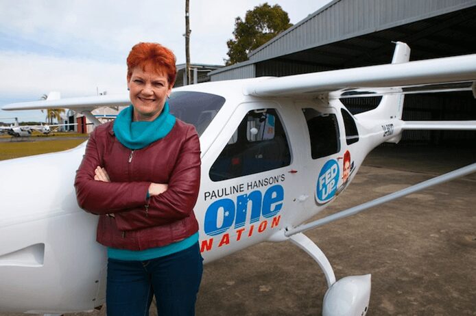 A woman standing confidently beside a small airplane with campaign logos.