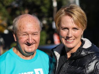 Smiling elderly man and middle-aged woman outdoors on a sunny day.