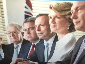 Four people in formal attire seated at a table with a British flag in the background.