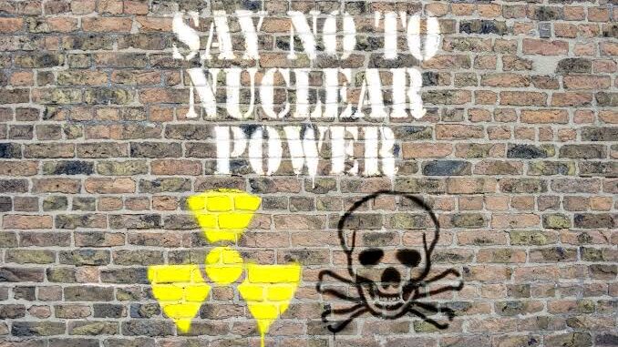 Graffiti on a brick wall saying 'SAY NO TO NUCLEAR POWER' with nuclear and skull symbols.