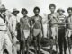 A historical black-and-white photo of Indigenous men wearing traditional attire.
