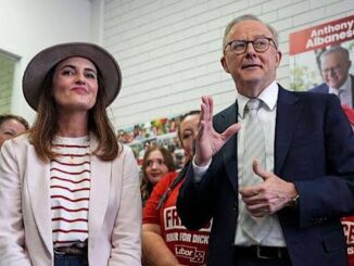Two people speaking at an event with an audience behind them.