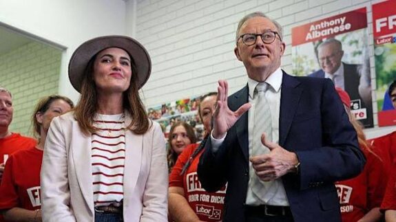Two people speaking at an event with an audience behind them.