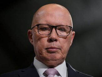 Serious bald man wearing glasses and a suit.