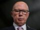 Serious bald man wearing glasses and a suit.