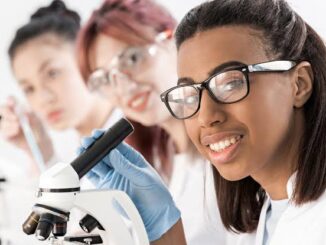 Students examining specimens using a microscope in a science class.