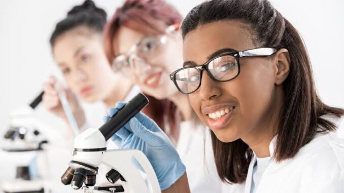 Students examining specimens using a microscope in a science class. Students examining specimens using a microscope in a science class.