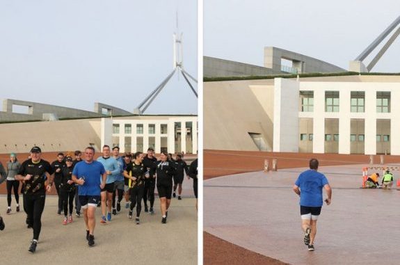 People jogging near a modern building with a wind turbine in the background. People jogging near a modern building with a wind turbine in the background.