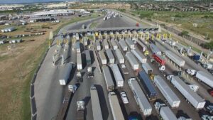A busy toll plaza with multiple trucks and vehicles waiting in line.