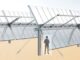 Person standing near a large solar panel structure with support beams.