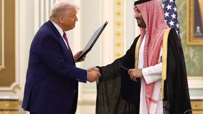 Donald Trump shaking hands with a Saudi royal in traditional attire.