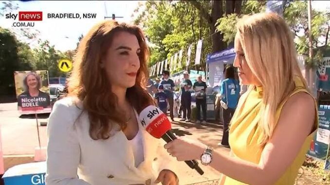 Two women engaged in an outdoor interview under sunny conditions.