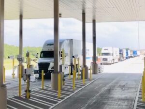 Trucks lined up at a toll booth on a highway.